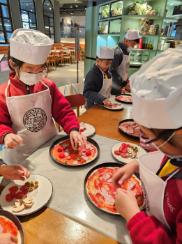 Students follow instructions to    make a pizza in the restaurant.